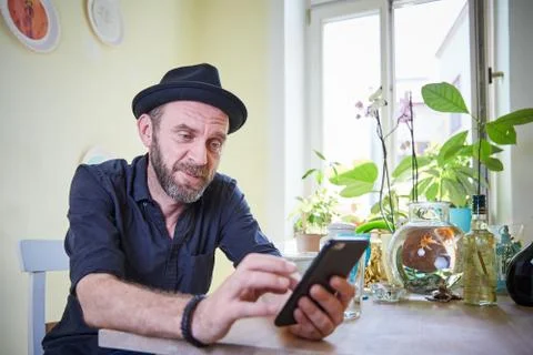 Hipster with beard and hat looking at iphone Foto stock