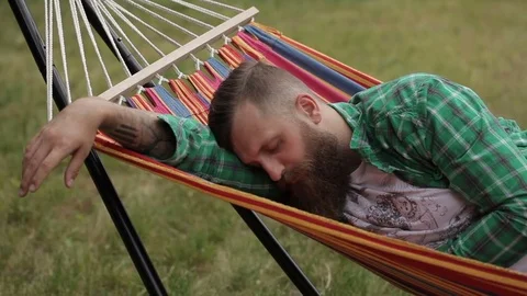Hipster with a beard sleeping on a hammock Stock Footage 77167526