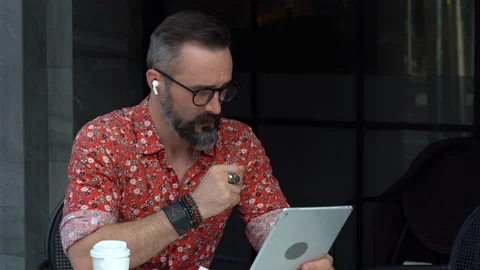 Hipster bearded man using tablet and earphones video conference at coffee sho Stock Footage 154848453
