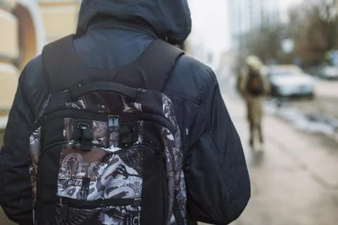 Hipster boy with backpack walking through city street Stock Photos