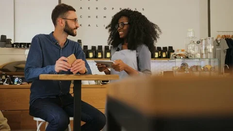 Hipster caucasian man making an order in the cafe using menu while waitress Stock Footage 78654711