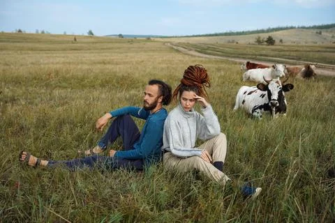 Hipster couple posing in the fields with cows Stock Photos