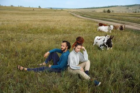 Hipster couple posing in the fields with cows Stock-Fotos