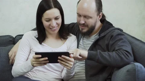 Hipster couple using tablet on couch at home in the living room Stock Footage 68725062
