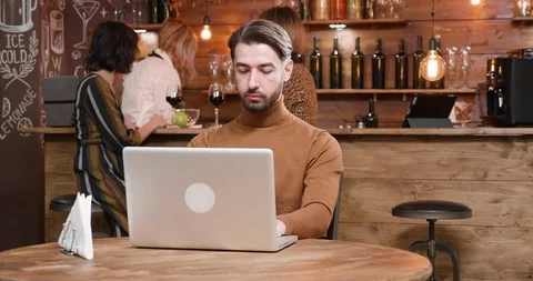 Hipster freelancer being served coffee while working at his laptop Stock Footage 103043720