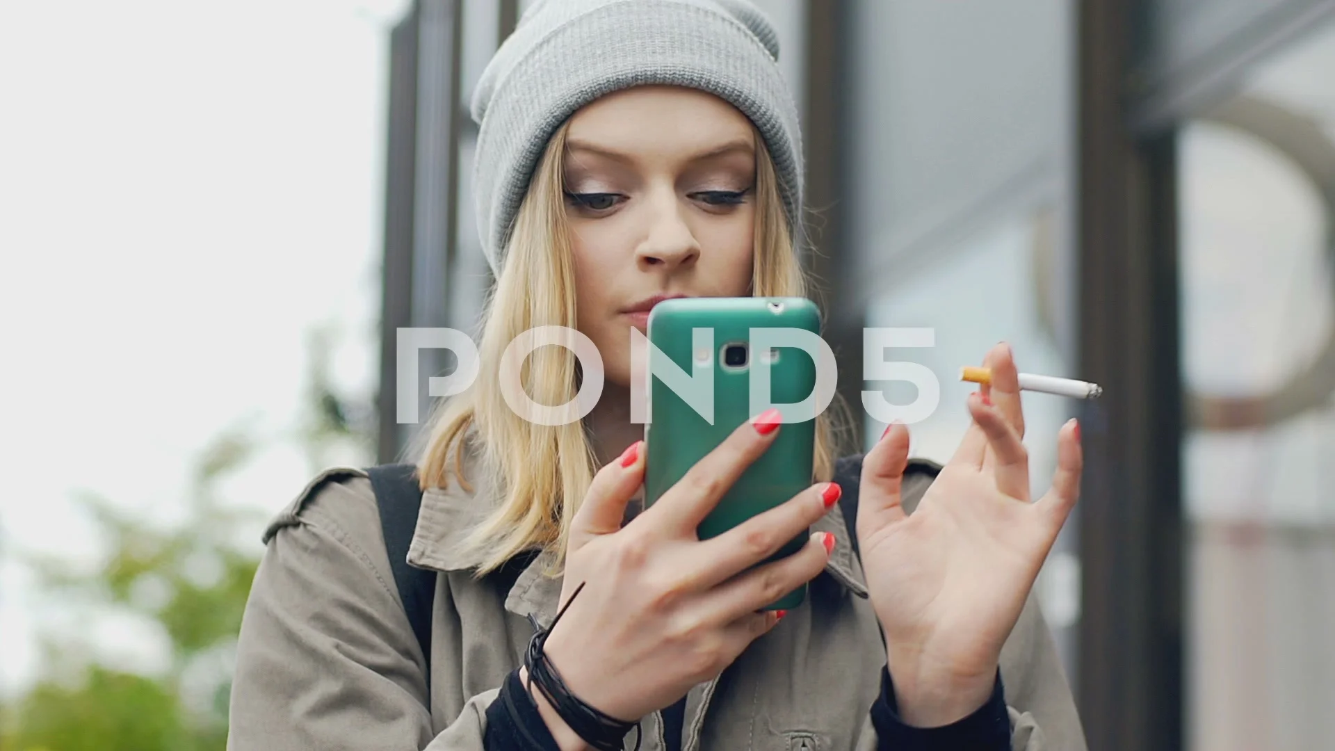 Hipster girl smoking cigarette and browsing internet on smartphone