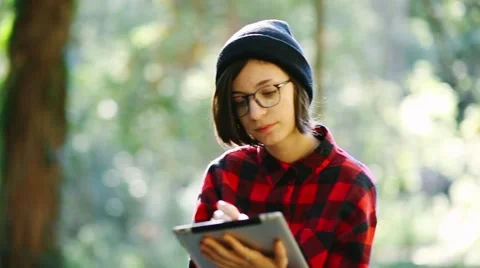 Hipster girl using digital tablet in the forest. Handheld shot Stock Footage 47314394