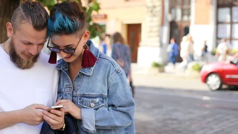 Hipster guy with a beard and hipster girl in jeans jacket looking at something Video stock 100731598