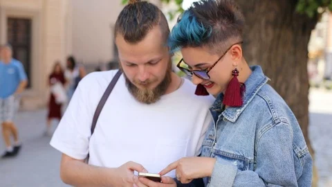 Hipster guy with a beard and a hipster girl in jeans jacket looking at something Video stock 100731602
