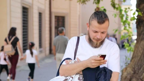 Hipster guy with a beard with a smartphone in his hand in a t-shirt the camera Video stock 100731579