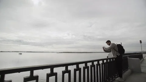 Hipster guy with beard taking photo of river on his camera phone in travel Stock-Footage 132490330
