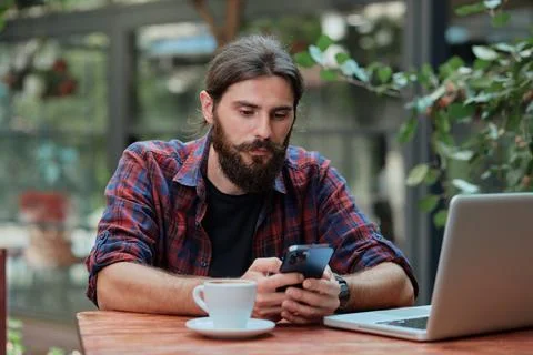 Hipster guy checking his smart phone in a cafe Foto stock