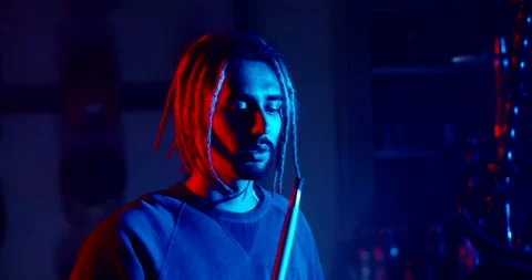 Hipster guy with dreadlocks looking at camera while smoking a hookah in neaon Vidéo 133355805