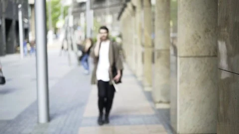 Hipster guy in glasses walking and talking on the phone outside 库存影片 77488964