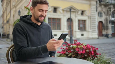 Hipster guy with mobile smart phone digital camera talks while sitting in cafe Stock Footage 137632762