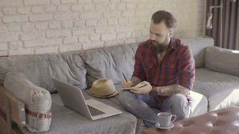 Hipster guy is taking some notes from his laptop Stock Footage 72533762