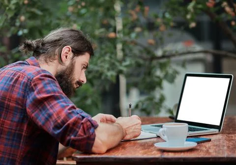 Hipster guy writing in a notebook in a cafe. Stock Photos