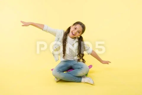 Hipster happy child pretend flying on penny board on yellow background. Little Stock Photos