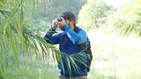 Hipster man with beard and backpack taking photos in nature Stock Footage 139611575