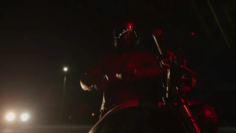 Hipster man in black leather jacket stands in front of his motorcycle in light Видео 292774601