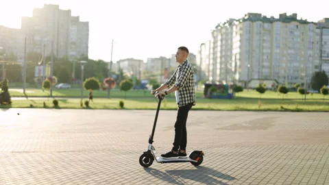 Hipster man commuting to work through city on electric scooter. Eco-friendly Stock Footage 194603812