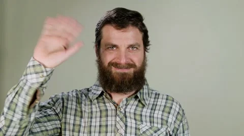 Hipster man says hello in camera on neutral background Stock Footage 58850574