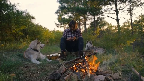 Hipster man smoking a cigarette sitting in forest near campfire Stock-Footage 84425893