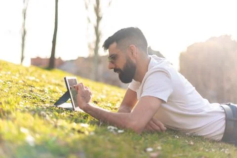 Hipster Man Using a digital Tablet in a Park. Stock Photos