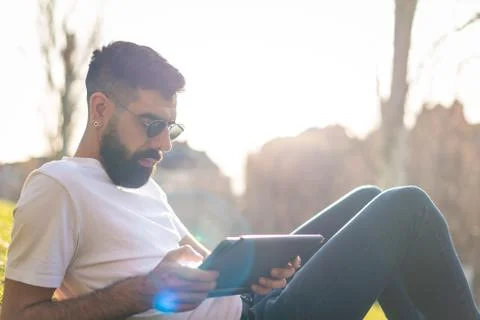 Hipster Man Using a digital Tablet in a Park. Stock Photos