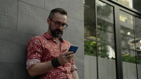 Hipster man is using his mobile phone to keep in touch Stock Footage 169458646