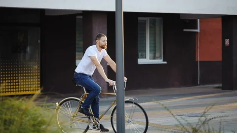 Hipster  with red bread rides a bicycle in city park Stock Footage 121130550