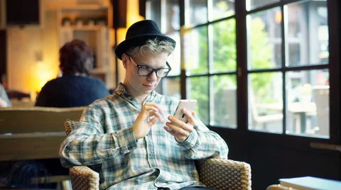 Hipster sitting in the cafe and doing selfies on smartphone 스톡 동영상 62407560