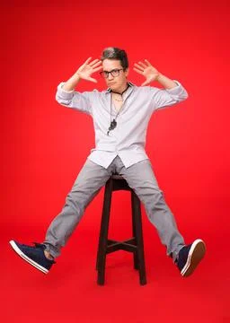 Hipster sitting on a high stool with both legs raised Foto stock