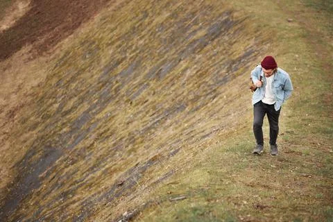Hipster traveler in casual outfit walking in nature, climb the Hill, man walks Stock Photos
