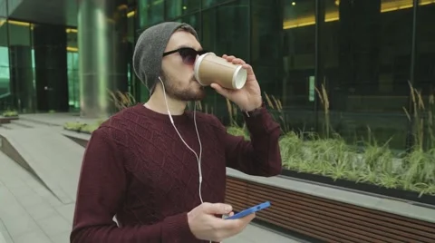 Hipster using app and listening to music in headphones, drinking coffee Stock Footage 68398881