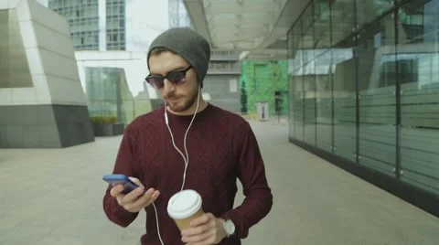 Hipster using app and listening to music, drinking coffee and walking Stock Footage 68399008
