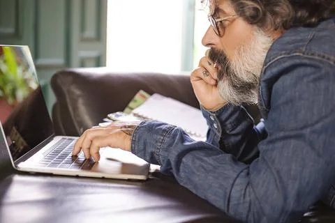 Hipster using a laptop on the sofa at home Stock Photos