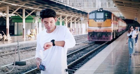 Hipster waitng for train in train station, using phone. Asian man. Video stock 106384834