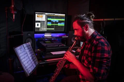 Hipster withe young man is playing on musical instrument in the studio to record Stock Photos
