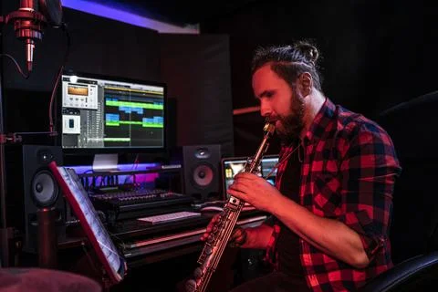 Hipster withe young man is playing on musical instrument in the studio to record Stock Photos