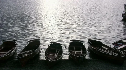 Hire rowing boats, backlit by the setting sun, on the shore of Lake Windermere Stock Footage 51215542