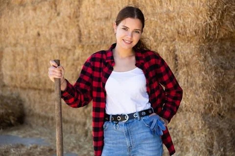 Hired cow farm worker posing in barn against background of hay bales Stock Photos