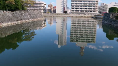 Hiroshima Castle moat reflecting the surrounding modern city buildings Stock Footage 335574661