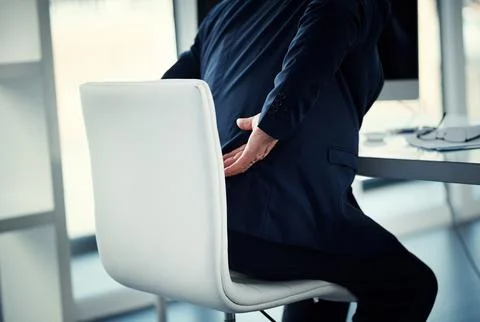 His back is carrying his workload. a businessman experiencing back ache while Stock Photos