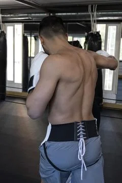 With his back turned, a boxer hitting the punching bag Stock Photos