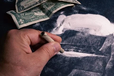 In his hand there is a dollar rolled into a tube over a line of cocaine, wi.. Stock-Fotos