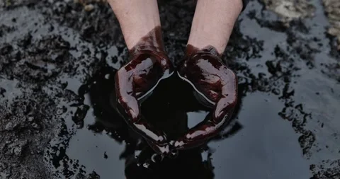 His hands are stained with crude oil against the background of spilled Stock Footage 345519349