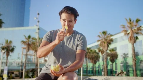 Hispanic alluring healthy guy sitting on beach side enjoying eating fresh melon Stock Footage 109419281