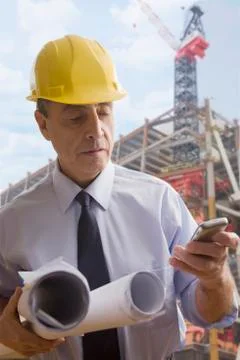 Hispanic architect using cell phone at construction site Stock Photos