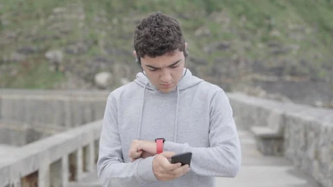 Hispanic athlete checking smartwatch and comparing results on phone Stock Footage 217371760